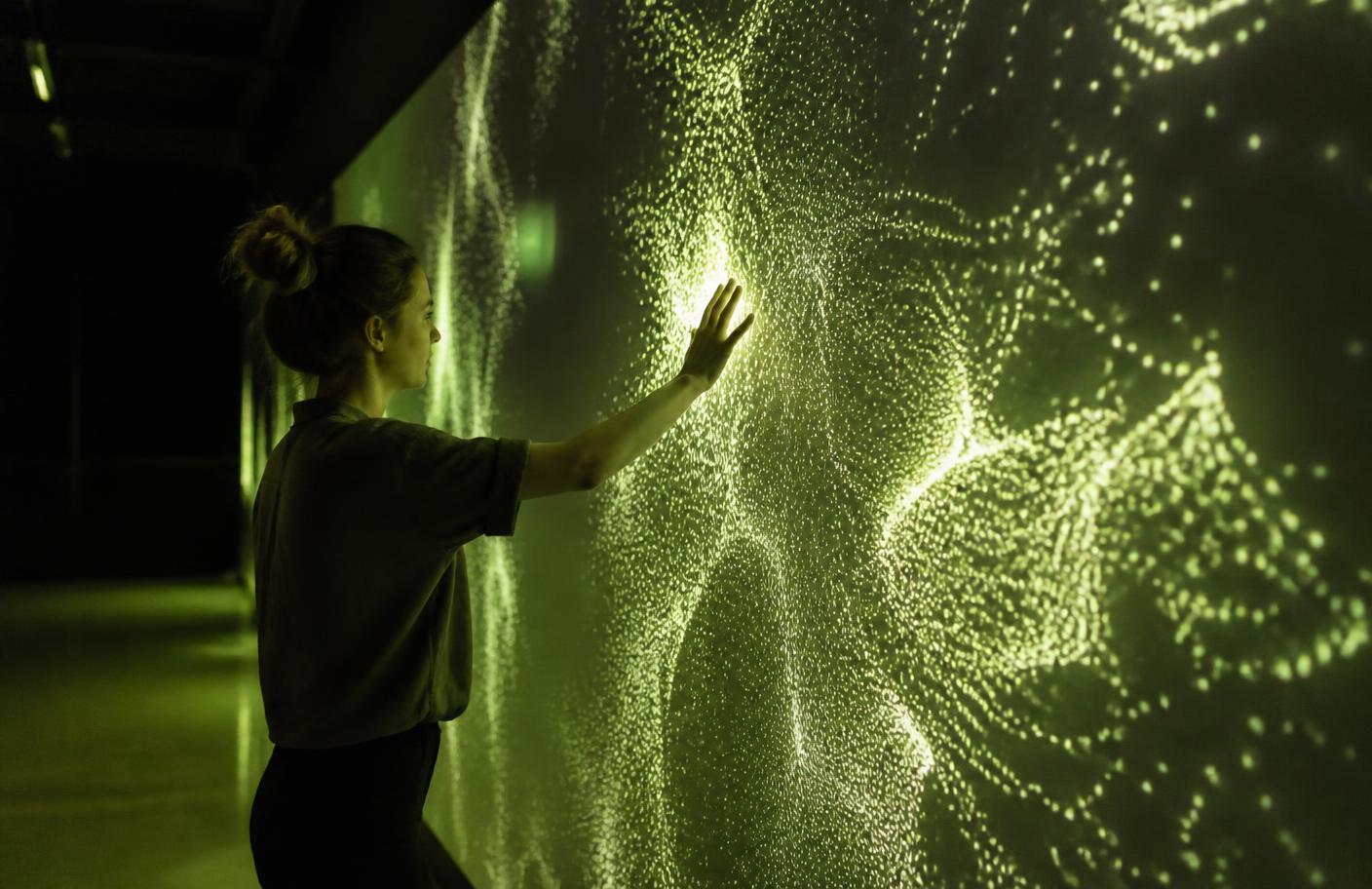Visitor touching a responsive interactive light installation