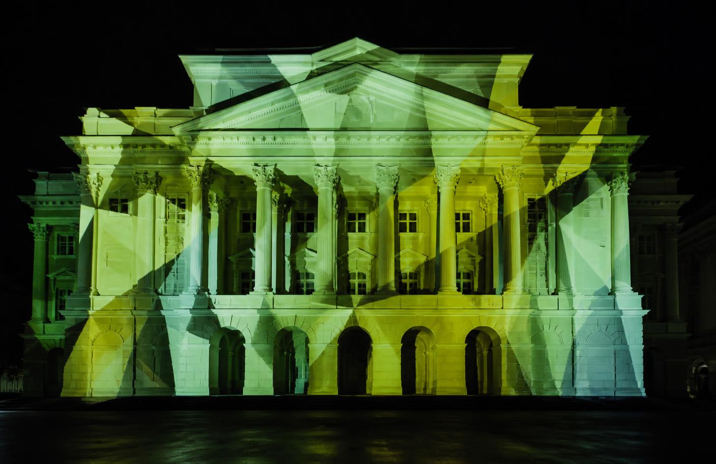 Projection-mapped light patterns wrapping a large architectural facade at night