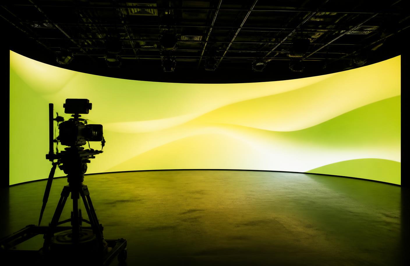 Curved LED volume wall glowing with gradient content in a dark studio